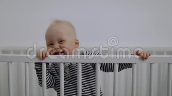 可爱的微笑男孩在童床上玩耍视频的预览图