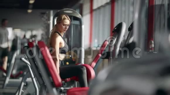 漂亮的女人在健身俱乐部的运动模拟器上做健身运动视频的预览图