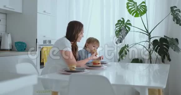 妈妈帮小儿子在厨房吃汉堡视频的预览图