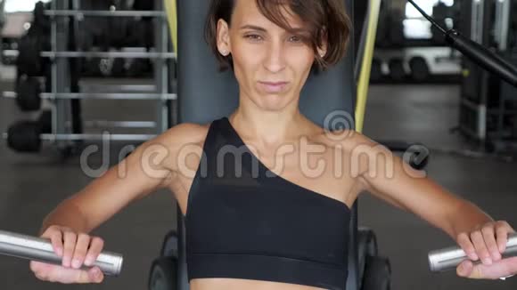 运动的女人正在训练机器上练习手臂肌肉视频的预览图