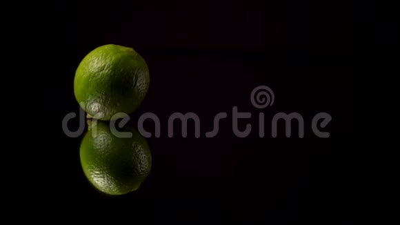 绿色新鲜石灰或绿色柠檬卷在黑色背景上的镜子视频的预览图