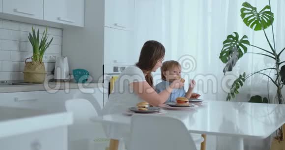 妈妈帮小儿子在厨房吃汉堡视频的预览图