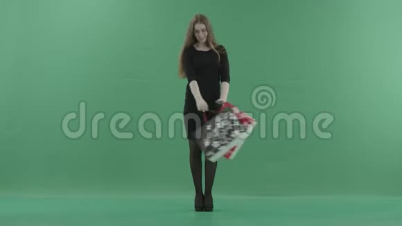 美丽快乐的女人穿着黑色的小裙子摆姿势用购物袋旋转她站在工作室里视频的预览图