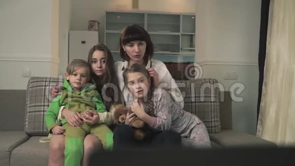 一家人坐在客房的沙发上有感情地看电视年长的姐妹和年幼的孩子花时间视频的预览图