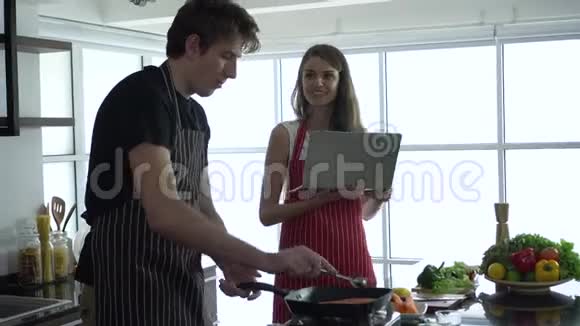 高加索夫妇用笔记本电脑上网烹饪食谱视频的预览图