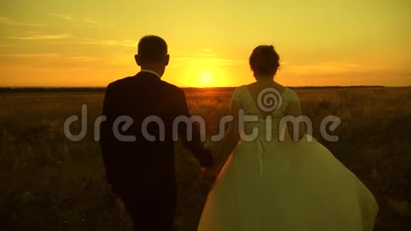 恋爱中的情侣牵着手走向日落快乐的男人和女人在日落时跑步恋爱中的情侣在度蜜月视频的预览图