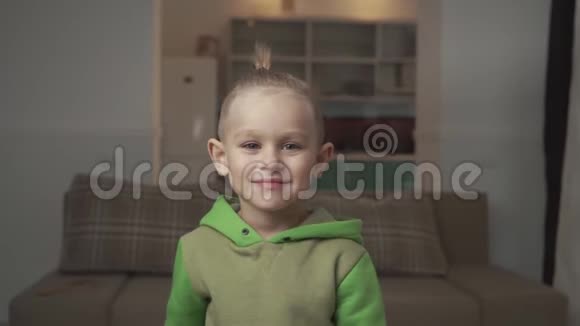 小男孩的肖像时尚的发型站在沙发的背景在家里视频的预览图