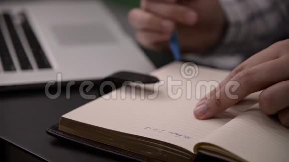 男人穿着格子衬衫用蓝色铅笔在笔记本上写字视频的预览图