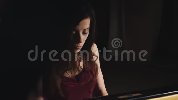 穿紫色衣服的女人在黑暗的音乐厅里弹钢琴视频的预览图