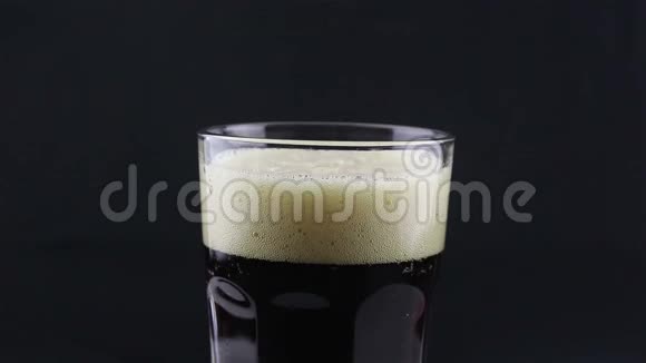酒保把黑啤酒从瓶子里倒入玻璃杯里一个人把一杯黑啤酒装满视频的预览图