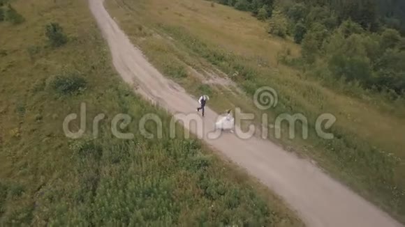 新郎和新娘在山上奔跑空中无人机射击视频的预览图