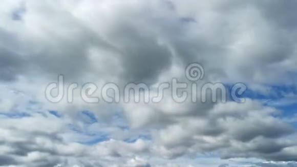 在阳光明媚的日子白色和灰色的蓬松云在晴朗的蓝天上翻滚大自然云景视频的预览图