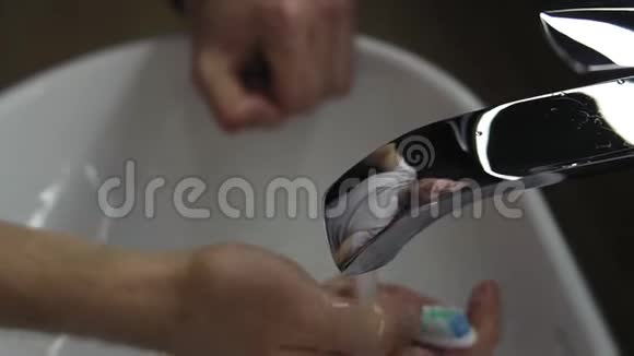 男性在家里的浴室刷牙后用手冲洗牙刷面反射在银沉上关门视频的预览图