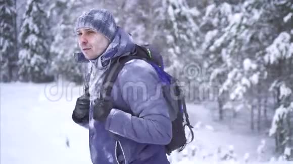 冰雪覆盖的游客背着背包穿过树林视频的预览图