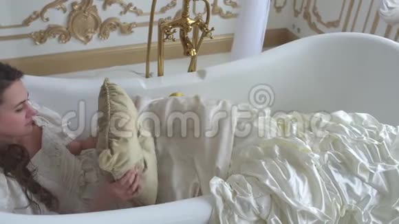 穿球衣的陌生女孩把枕头放在头底下躺在浴缸里睡得很近视频的预览图