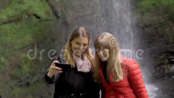 两个女孩在爱尔兰的瀑布前自拍视频的预览图