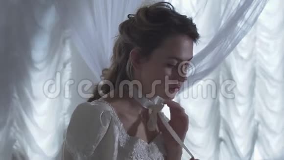 年轻漂亮的女人围着白色的网帘坐着脖子上系着一条丝带视频的预览图