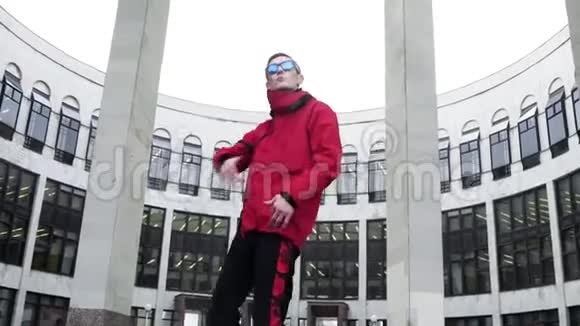 穿着红色运动服和太阳镜的酷男人在花岗岩柱旁边狂欢视频的预览图