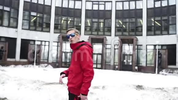 穿着红色运动服和太阳镜的好男人在灰色的大建筑旁边咆哮视频的预览图