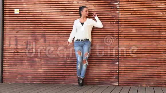 女孩站在一堵木墙旁为照相机摆姿势视频的预览图