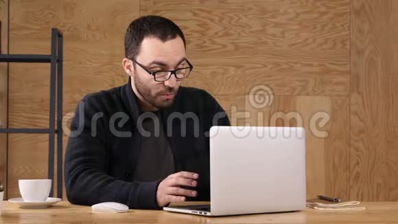 快乐留胡子的嬉皮士挥舞着手在视频聊天中交谈使用高速互联网在笔记本电脑上进行良好的连接视频的预览图
