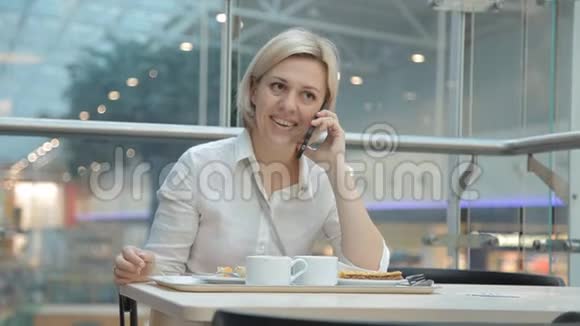 一个穿黄色裤子的女人带了一件带食物的衣服在一家餐馆的桌子旁坐下视频的预览图