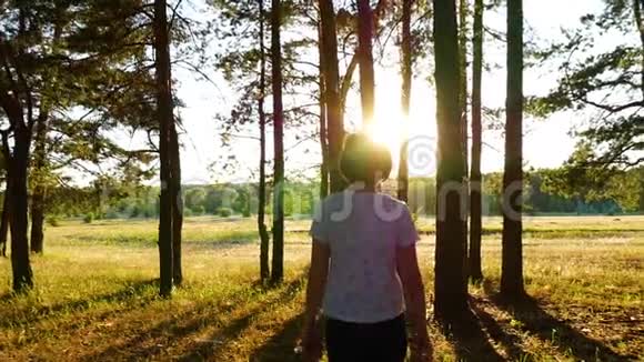 这个女孩在夏天日落时在阳光下穿过树林休息散步独处相机跟着一个视频的预览图