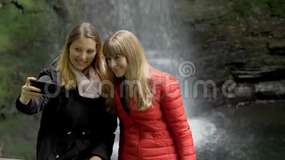 两个女孩在爱尔兰的瀑布前自拍视频的预览图