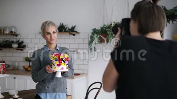 女性糖果师在她的厨房里用鲜花蛋糕装饰拍照的过程来自视频的预览图