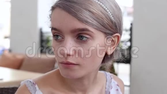穿着夏装坐在咖啡馆摆姿势的年轻美女特写视频的预览图