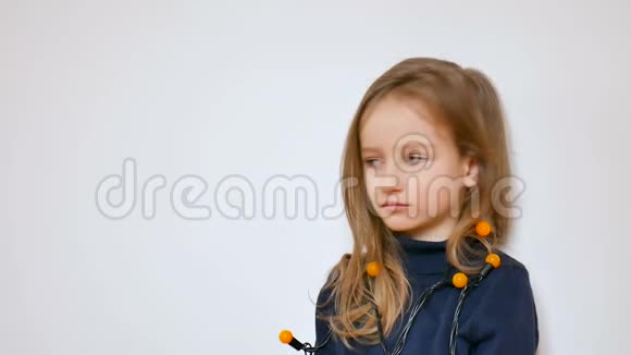 一张可爱的小女孩的冬季画像她留着长长的金发和蓝色的大眼睛戴着一束黄色的圣诞灯视频的预览图