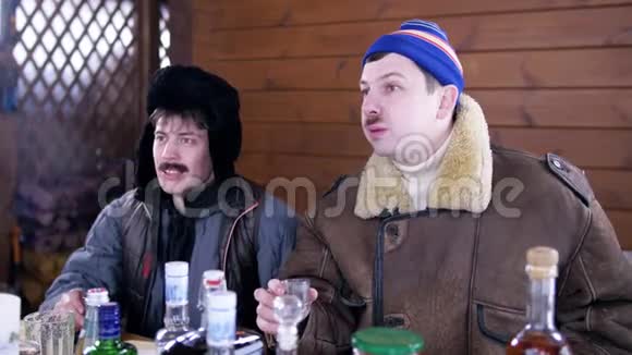 在乡间别墅里两个穿着冬装的男人围着桌子坐着笑视频的预览图