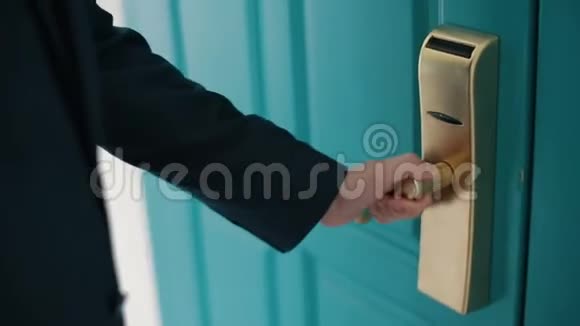 穿着深蓝色西装的人打开一扇巨大的绿松石门进入一个房间关上门把手视频的预览图