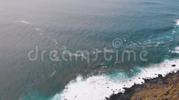 空中海浪以泡沫撞击着黑色的海滩视频的预览图