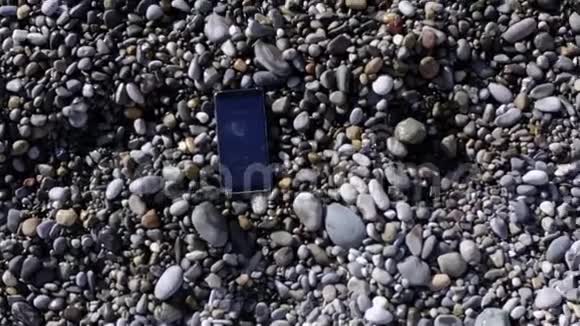 从飞行无人驾驶飞机上拨打手机躺在海边的卵石滩上视频的预览图