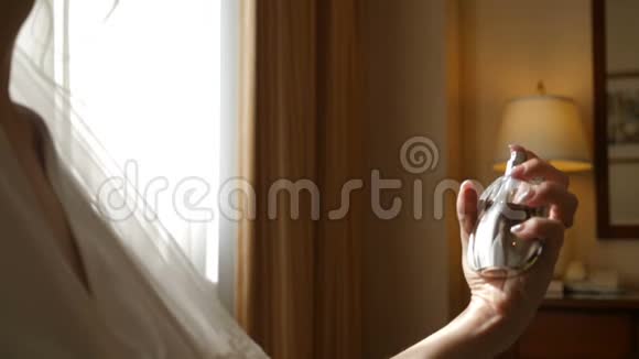 婚礼当天新娘在酒店房间里使用香水无名女子慢动作喷香视频的预览图