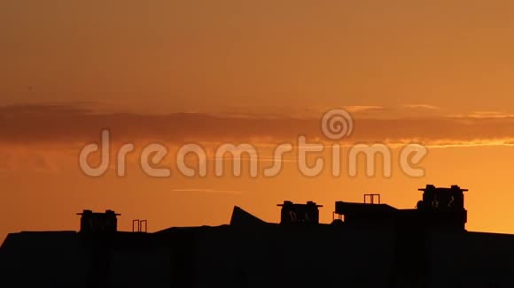 城市上空日落云彩飘过明亮的橙色天空在地平线上可见的城市房屋屋顶视频的预览图