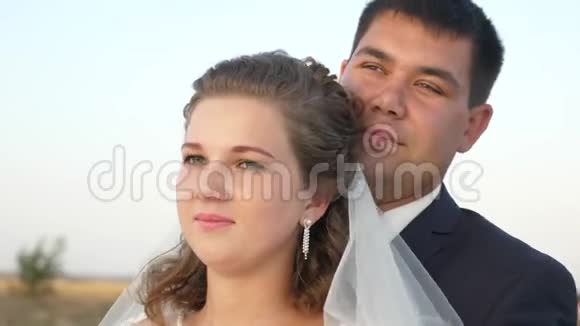 男人和女人拥抱在一起跳舞看着远方微笑着蜜月新婚夫妇带着面纱和白色的新娘视频的预览图