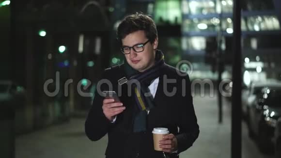 一个人在夜里沿着马路走着拿着电话喝了一口咖啡视频的预览图