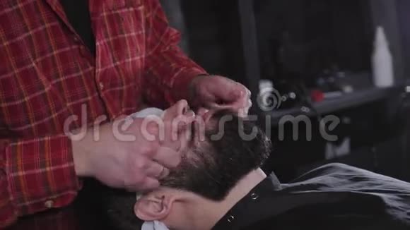 在理发店用剪刀特写专业的梳洗胡须希普斯特概念一个留胡子的嬉皮士的肖像视频的预览图