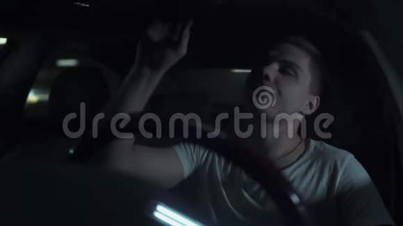 年轻人的画像照镜子在黑暗中纠正坐在车里的头发视频的预览图