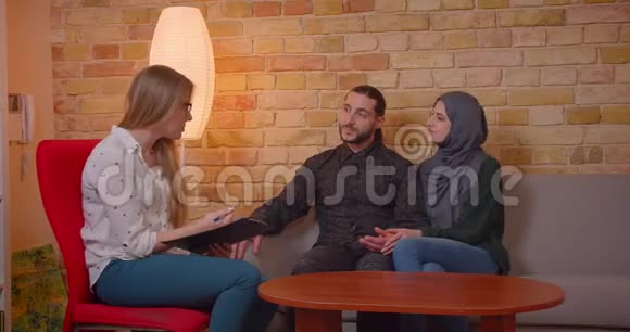 一对年轻快乐的穆斯林夫妇和一个现实的人讨论一间新公寓时他们兴高采烈地坐在公寓上视频的预览图