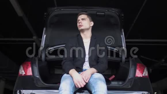 放松的年轻人坐在敞篷车里嚼口香糖一个人在地下停车场等车视频的预览图