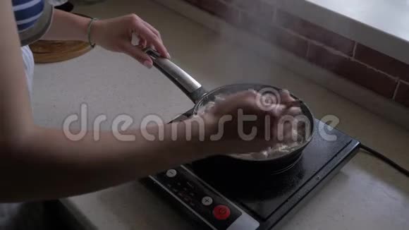 女人用洋葱和奶油煎锅搅拌蘑菇视频的预览图