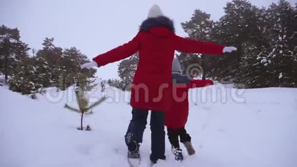 快乐的十几岁的女孩在雪地上奔跑在飞行中伸直手臂在松儿的新鲜空气中漫步视频的预览图