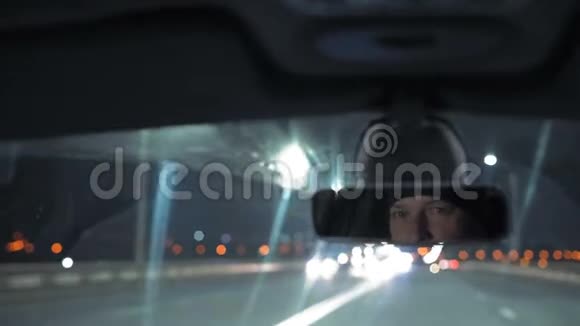 特写镜头男人看着车在夜城行驶的后视镜视频的预览图