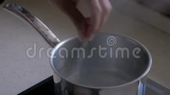 在金属平底锅中加入盐到沸水中视频的预览图