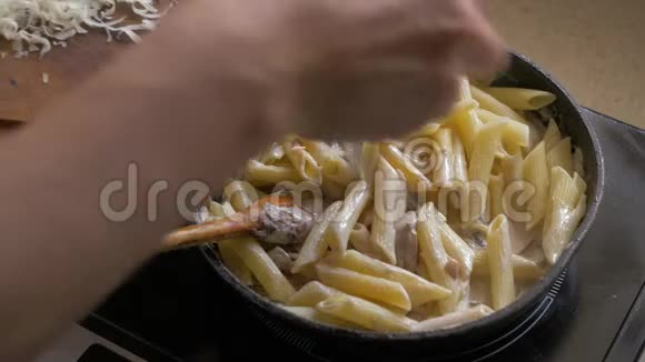 一只雌性的手把磨碎的奶酪加入到意大利面中这些奶酪是在平底锅里煎的视频的预览图