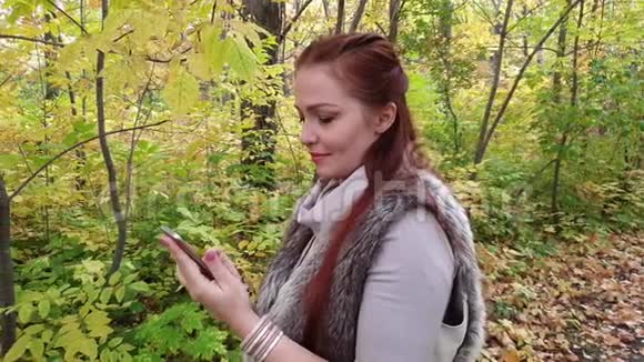 秋天公园的迷人女子带着电话视频的预览图