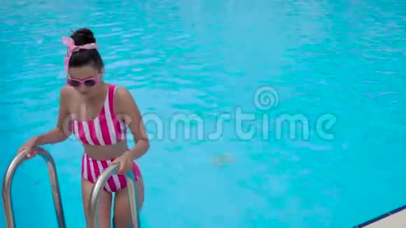 穿着条纹粉色泳衣的年轻女孩潜入游泳池视频的预览图